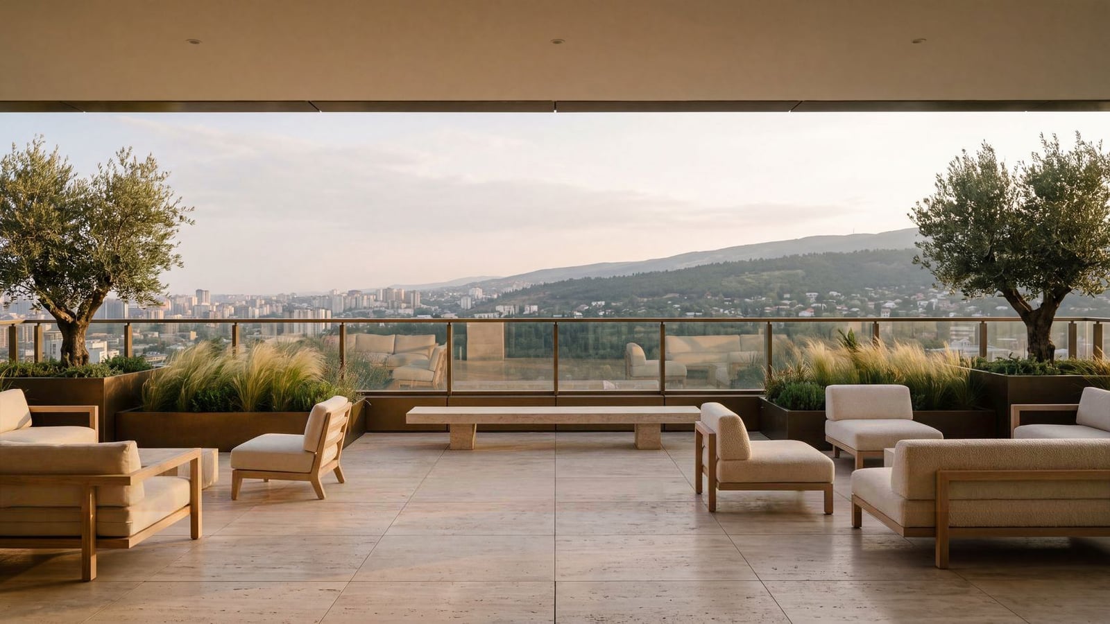 The sky terrace under a deep soffit, lounge seating and olive trees in planters along a glass balustrade, open to the park, the city and the ridge beyond.
