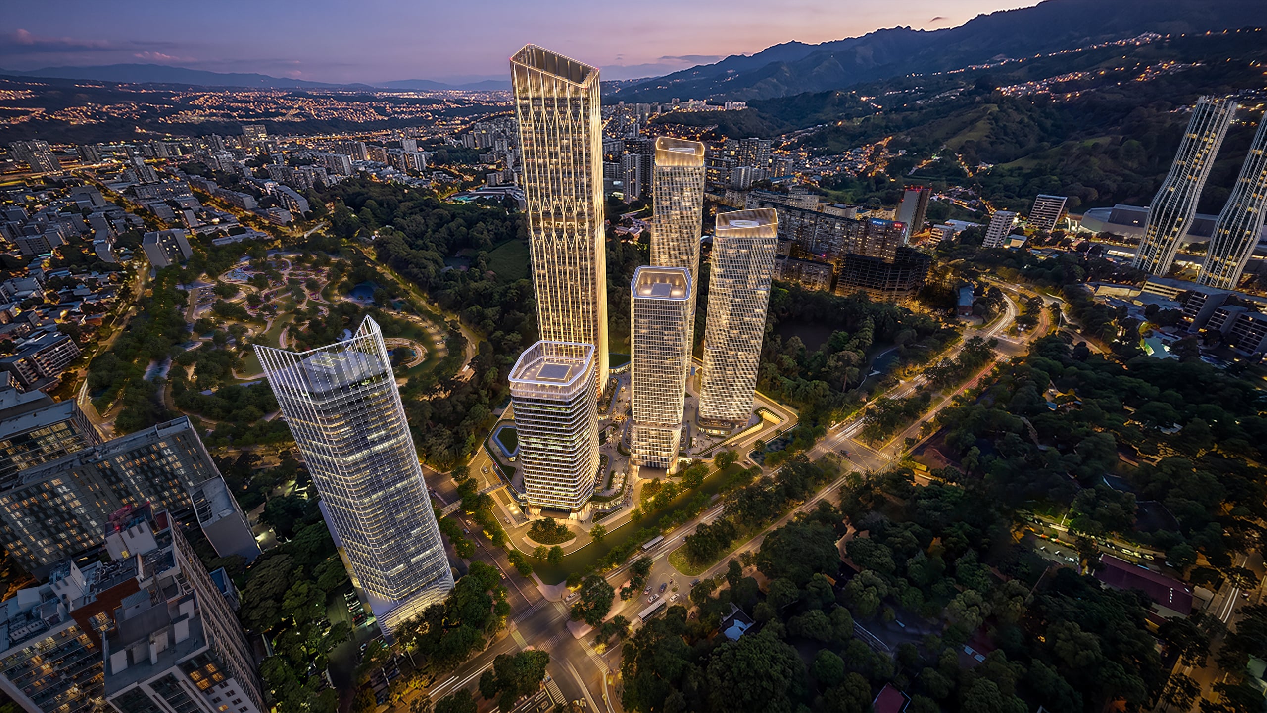 Trump Tower Tbilisi lit at dusk, seen from the air above the Downtown Tbilisi towers, with the city and the hills beyond.