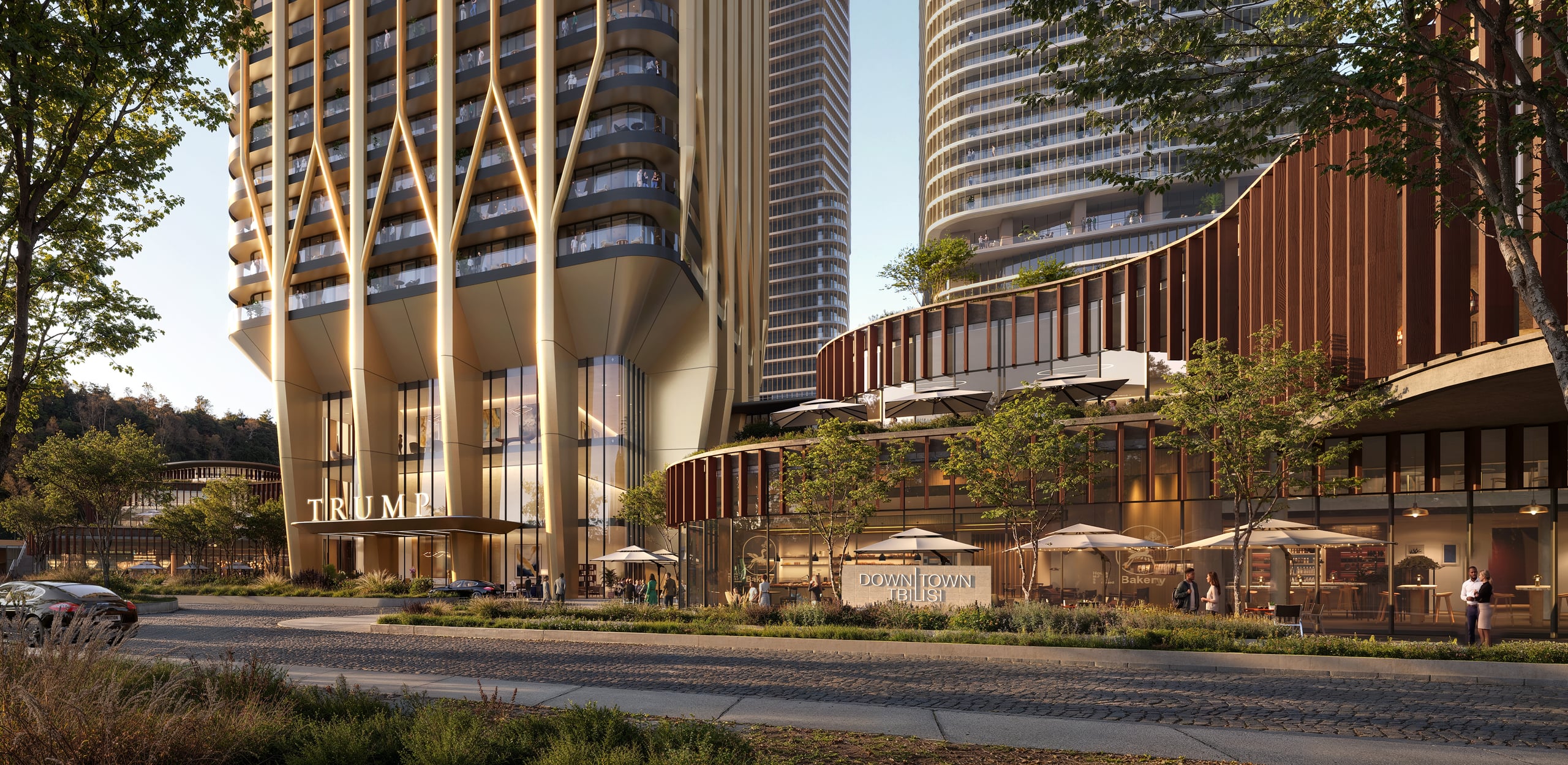 The base of the tower at street level, where the Y-shaped columns meet the shops and cafe terraces of the podium.